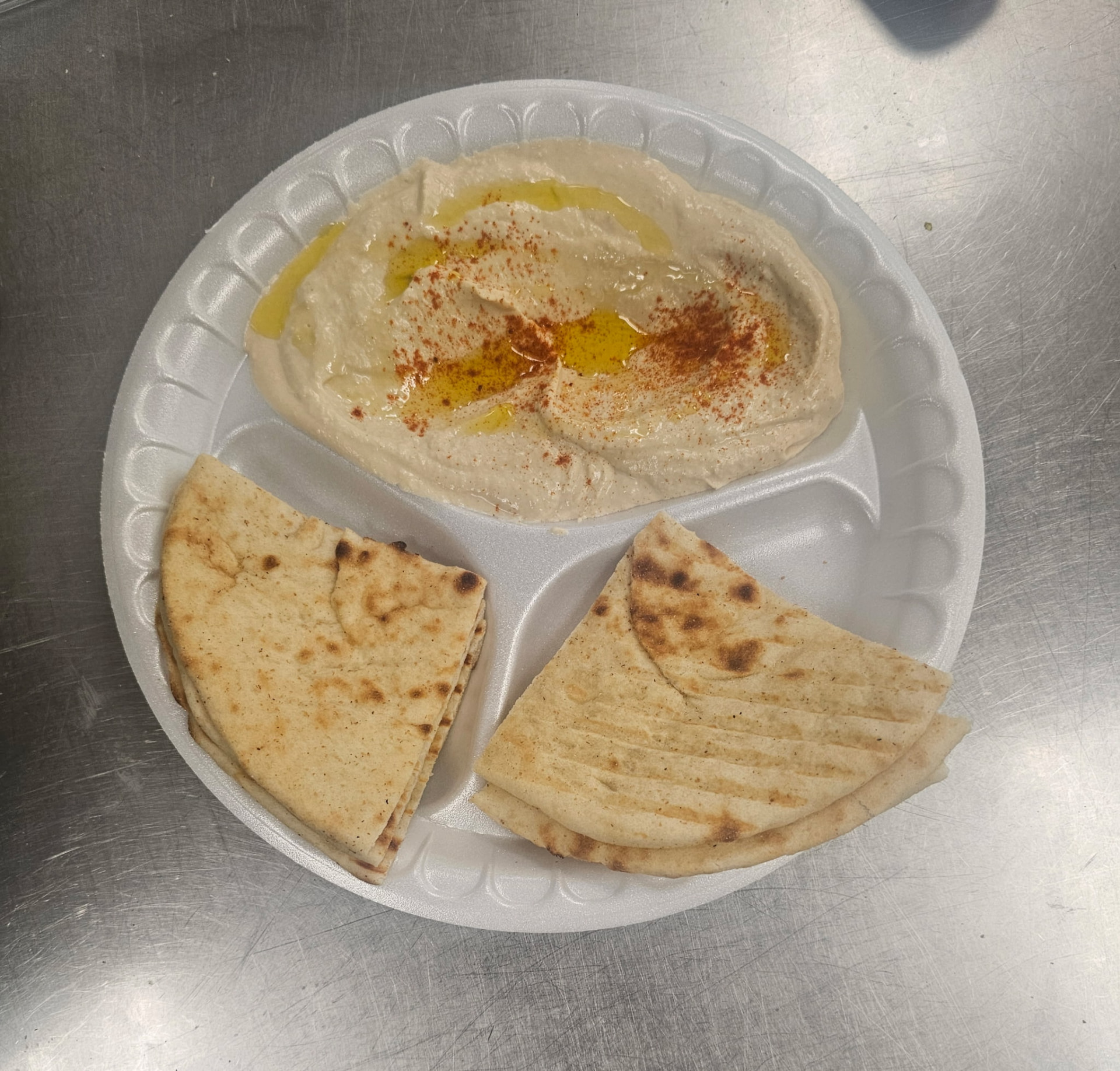 Fresh hummus with olive oil, paprika, and grilled pita